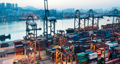 Container ships docked at a busy port with numerous shipping containers, cranes, and city buildings—where corporate law offices and lawyers in Chicago handle complex maritime transactions by the water.