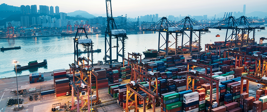 Container ships docked at a busy port with numerous shipping containers, cranes, and city buildings—where corporate law offices and lawyers in Chicago handle complex maritime transactions by the water.
