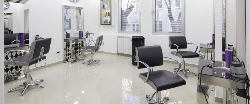 Modern hair salon interior with four black styling chairs, mirrors, shelves with hair products, and styling tools on counters in a bright, clean room—ideal for lawyers in Chicago to unwind after a busy day.