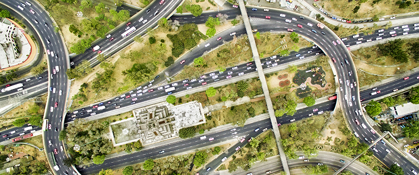 Aerial view of a busy multi-lane highway interchange with traffic, surrounded by green trees, grassy areas, and buildings—reflecting the dynamic environment where Chicago lawyers offer litigation support.