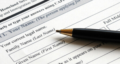 A black pen rests on a printed form requesting legal name information, including fields for family name (last name) and given name (first name), typically used in law offices or for litigation support.
