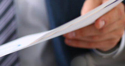 A person in a suit holds and reviews a stack of documents, with focus on their hand and the papers—reflecting the meticulous attention chicago lawyers bring to intellectual property law.