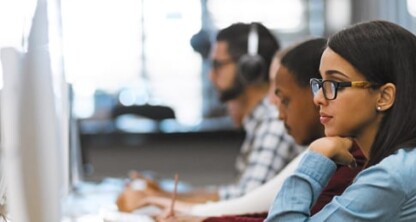People working at desktop computers in a row at an office or computer lab, with focus on a woman in glasses in the foreground, providing litigation support for lawyers in Chicago.
