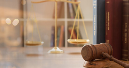 A wooden judge’s gavel rests on a desk in a corporate law office, with brass scales and legal books—perfect for lawyers in Chicago who specialize in intellectual property law.