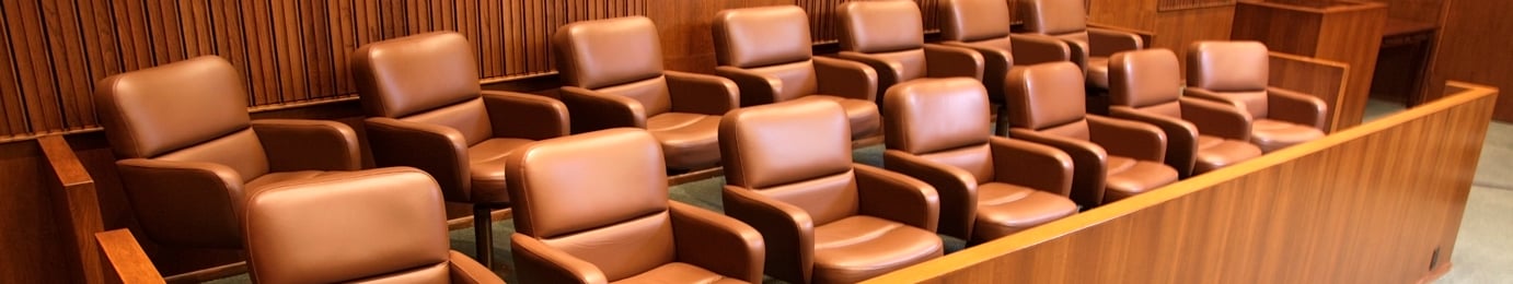 A row of empty brown leather chairs arranged in two tiers in a wooden jury box inside a courtroom, evoking the professional atmosphere found in a corporate law office or among top lawyers in Chicago.