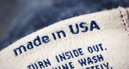A close-up of a clothing label with the words "made in USA" in blue text, along with partial care instructions below—ideal for use in a corporate law office focused on intellectual property law.