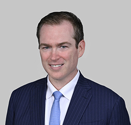 A man in a blue pinstripe suit, white shirt, and light blue tie poses in front of a plain gray background, reflecting the professionalism often seen at leading corporate law office settings with top lawyers in Chicago.
