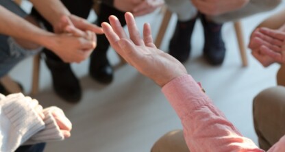 A group of people sitting in a circle, engaged in discussion at a corporate law office, with focus on hands gesturing while talking.