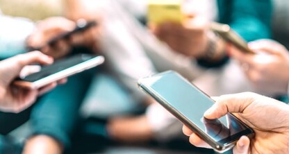 Several people sit close together, each holding and using a smartphone, with their hands and devices in focus—perhaps discussing matters related to intellectual property law or connecting with lawyers in Chicago.