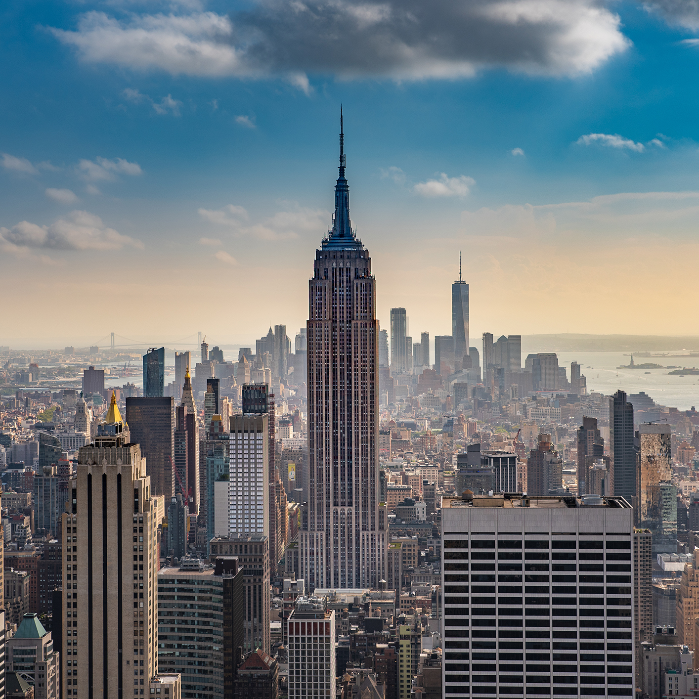 View of the New York City skyline with the Empire State Building in the center and other skyscrapers under a partly cloudy sky—an iconic scene reminiscent of dedication seen in top Chicago lawyers and their litigation support teams.