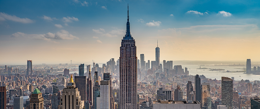 Aerial view of New York City skyline with the Empire State Building in the center, surrounded by skyscrapers under a partly cloudy sky—much like the energy found at leading law offices and litigation support teams.