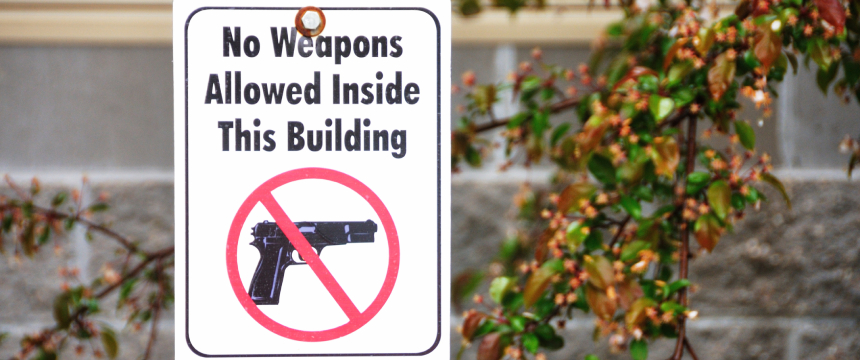 A sign at this corporate law office reads "No Weapons Allowed Inside This Building," with a crossed-out handgun image, indicating that firearms are prohibited for lawyers in Chicago and visitors alike.