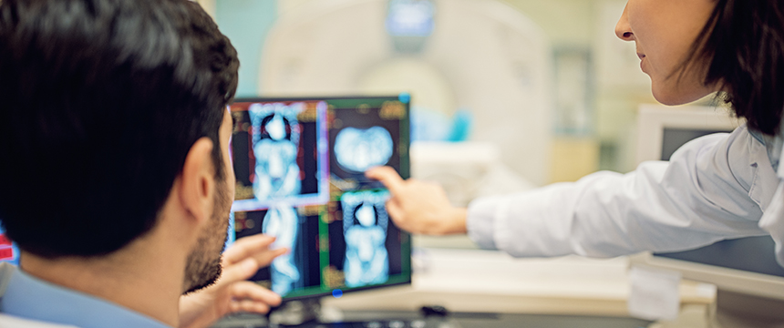 Two healthcare professionals examine and discuss medical scans displayed on computer monitors in a clinical setting, providing valuable insights often utilized by Chicago lawyers for litigation support.