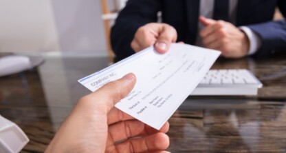 A person hands a check to another across a desk in a corporate law office, with a computer keyboard visible—typical of lawyers in Chicago providing litigation support.