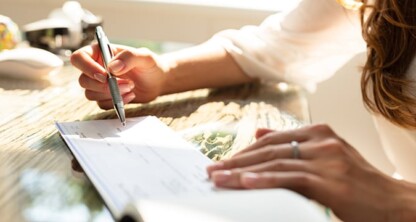 A person writes on a check with a pen while sitting at a desk in a corporate law office, highlighting the daily tasks handled by Chicago lawyers.