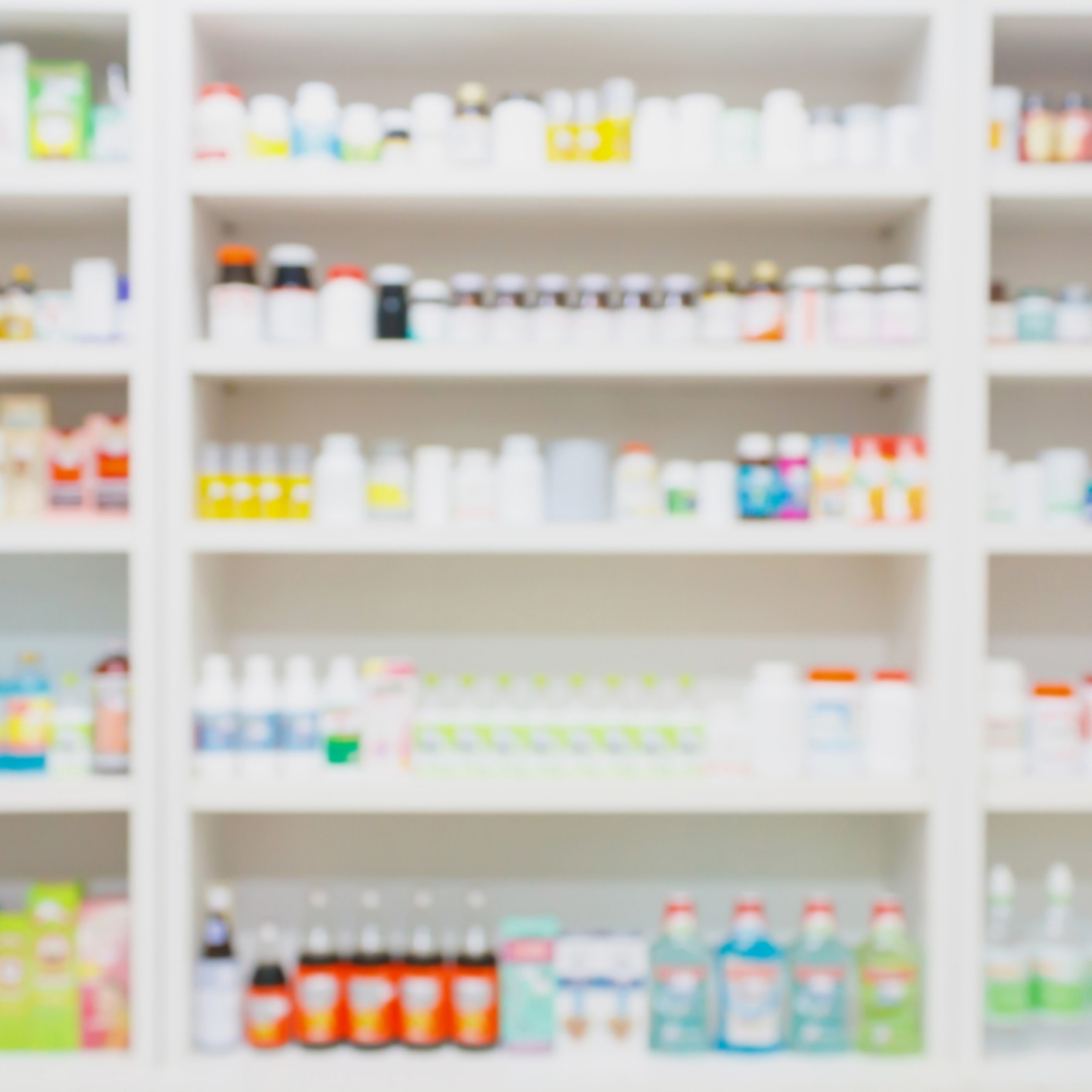 Blurry image of shelves stocked with various bottles and boxes of medicine and health products in a pharmacy, similar to the organized approach seen in law offices providing litigation support.