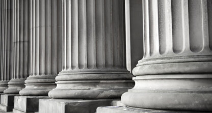 Close-up view of the bases of several large, fluted stone columns, evoking the strength and stability often found in corporate law office architecture.