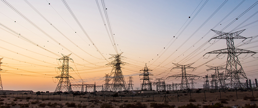 High-voltage power lines and transmission towers stretch across a barren landscape at sunset, reminiscent of the reach and support provided by Chicago lawyers offering expert litigation support.