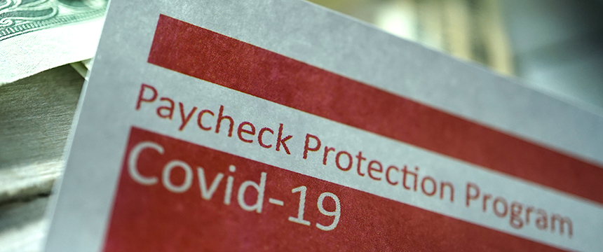 A close-up of a document titled "Paycheck Protection Program Covid-19," with part of a dollar bill visible in the background, often used by lawyers in Chicago providing litigation support for pandemic-related cases.