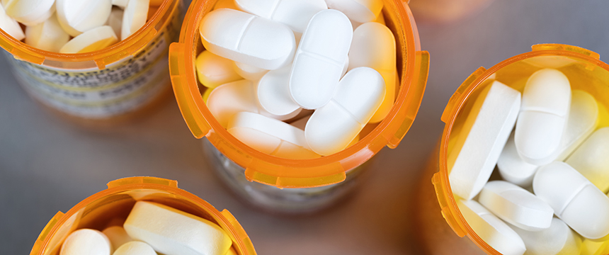 Five orange prescription bottles filled with white tablets and caplets, viewed from above on a plain surface—ideal for illustrating litigation support in a corporate law office.