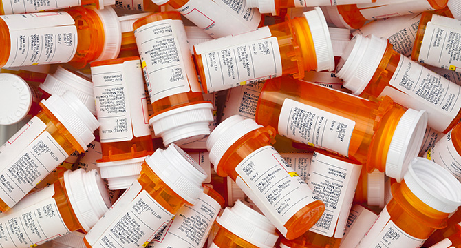 A pile of orange plastic prescription medication bottles with white labels and caps, some upright and some on their sides—often found as evidence in law offices handling cases for lawyers in Chicago.