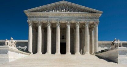 The front view of the United States Supreme Court building with tall columns, wide steps, and statues on both sides under a clear blue sky inspires law offices and litigation support teams nationwide.