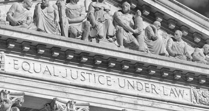 The marble facade of a courthouse, home to a leading corporate law office, features sculptures of figures and the inscription "EQUAL JUSTICE UNDER LAW" engraved below them.