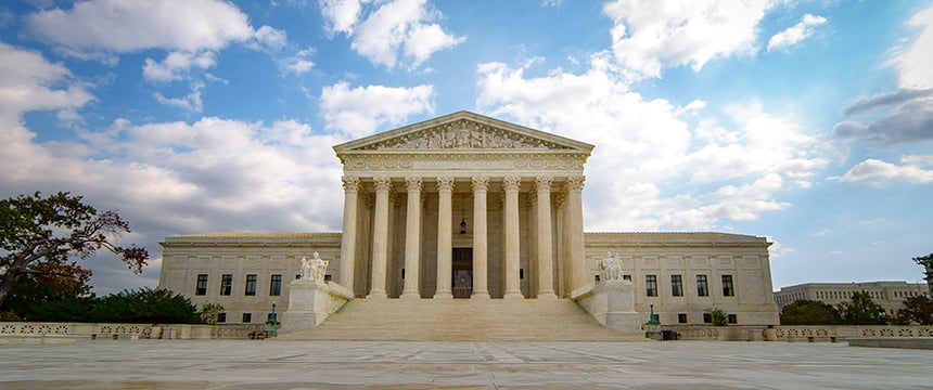 The front exterior of the United States Supreme Court building with columns and steps, under a partly cloudy sky—a symbol of justice that inspires law offices and litigation support across the nation.