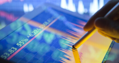 A hand uses a stylus on a tablet displaying colorful financial graphs and stock prices, set against a blurred background—an essential tool for lawyers in Chicago navigating complex corporate law office transactions.