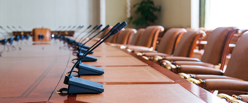 A long conference table with microphones and empty chairs arranged around it, ready for lawyers in Chicago to discuss intellectual property law and provide litigation support in a meeting room.