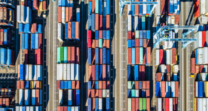 Aerial view of a shipping port showing rows of colorful cargo containers and cranes along multiple lanes, resembling the organized precision found in a corporate law office or the meticulous planning behind litigation support.