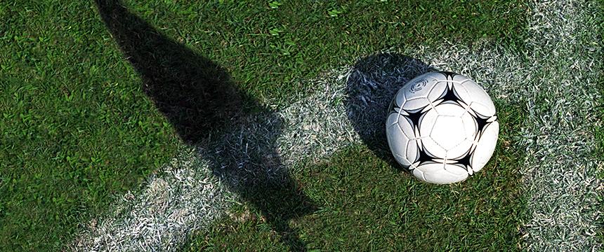 A soccer ball rests on a grass field near the corner arc, with the shadow of a corner flag visible on the ground—much like how litigation support provides guidance for lawyers in Chicago navigating complex cases.