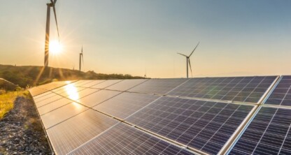 Solar panels and wind turbines in a rural landscape capture renewable energy under a clear sky at sunset, symbolizing innovation and sustainability valued by any forward-thinking corporate law office.