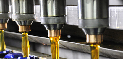 Close-up of multiple automated nozzles dispensing liquid into rows of containers on a production line, similar to the precision found in law offices or among Chicago lawyers specializing in intellectual property law.