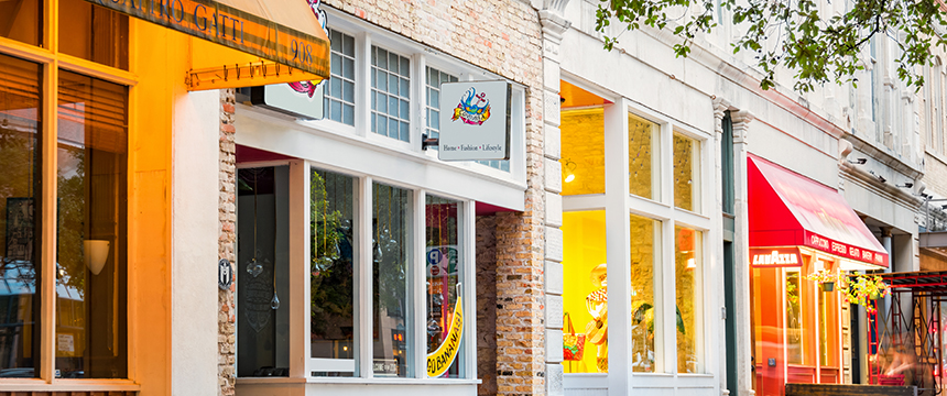 A row of storefronts on a city street, featuring large windows, colorful awnings, and signs for a bakery and chicago lawyers specializing in intellectual property law.