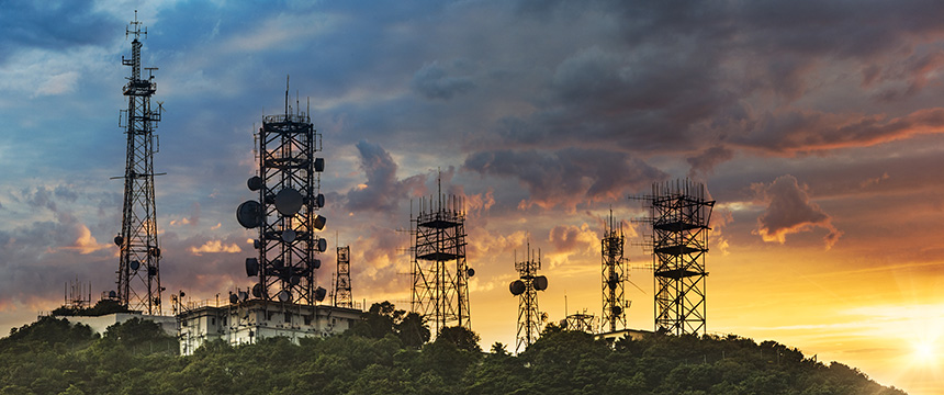 Several telecommunications towers with antennas and dishes stand on a hilltop against a dramatic sunset sky, reminiscent of the connectivity essential for modern chicago lawyers and corporate law office communications.