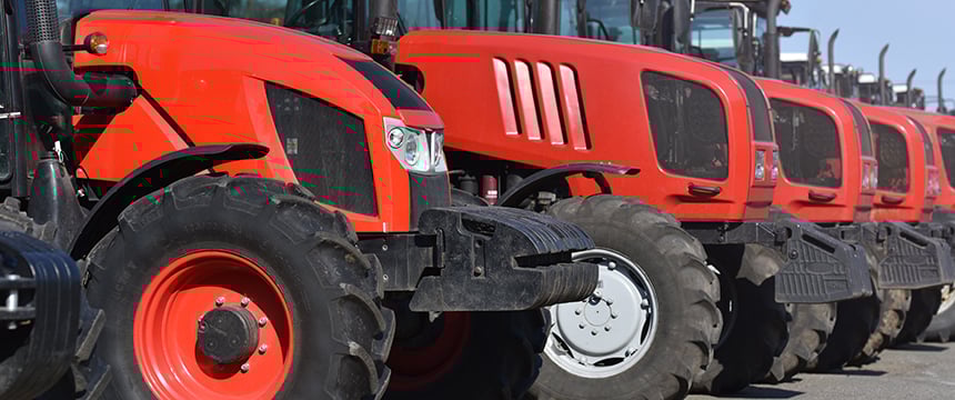 A row of red tractors parked side by side on a paved surface, viewed from the front left angle, reminiscent of the precision and order valued by top Chicago lawyers.