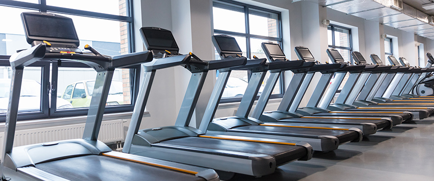 Row of treadmills lined up in a well-lit gym with large windows and natural light—perfect for lawyers in Chicago seeking a refreshing workout before heading to their corporate law office.