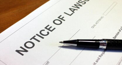 A close-up of a "Notice of Lawsuit" document and a black pen on a wooden surface, often seen in a corporate law office where lawyers in Chicago provide litigation support.