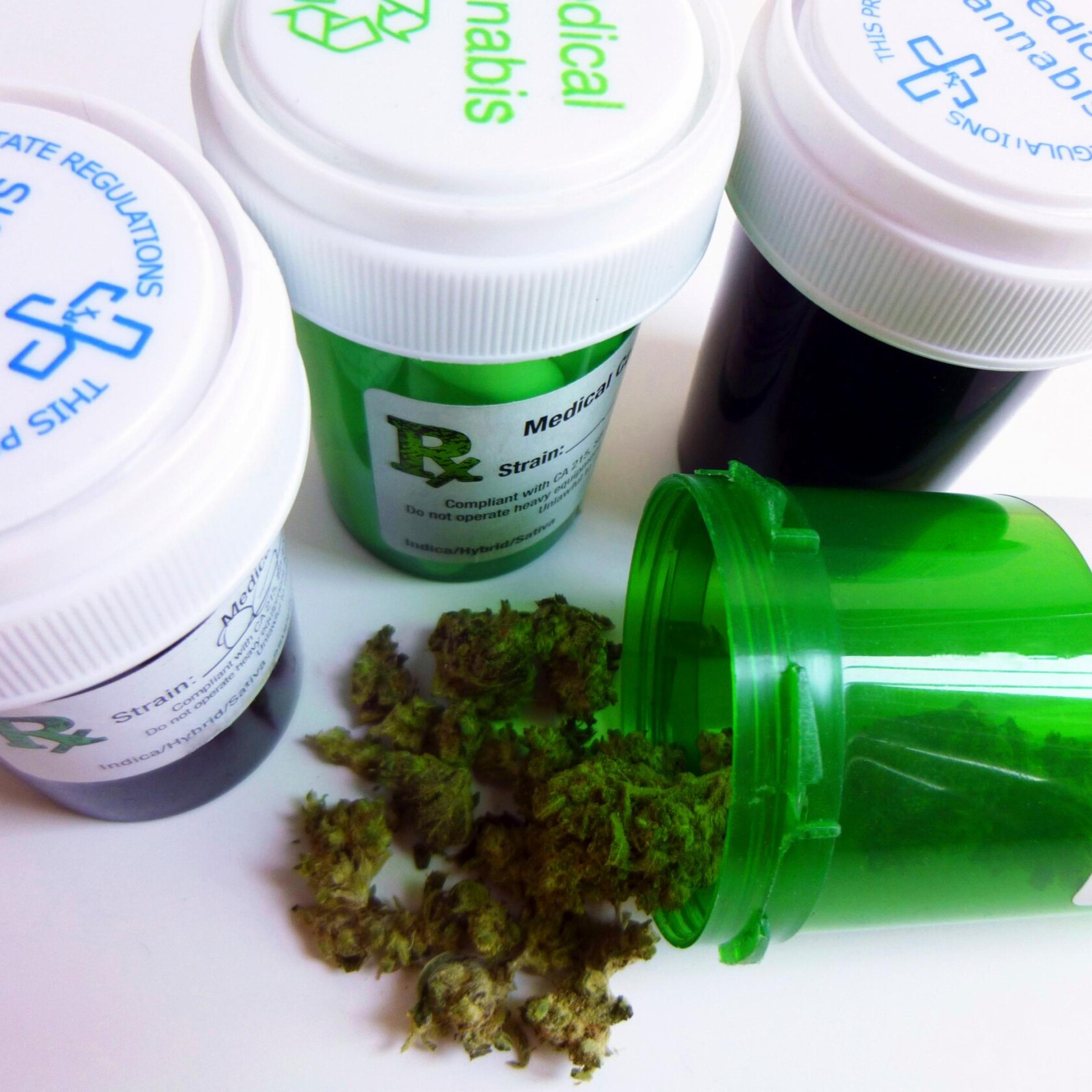 Four medical cannabis containers are shown, with one green container tipped over and dried cannabis buds spilling out—ideal imagery for litigation support or use in a corporate law office focused on cannabis regulation.