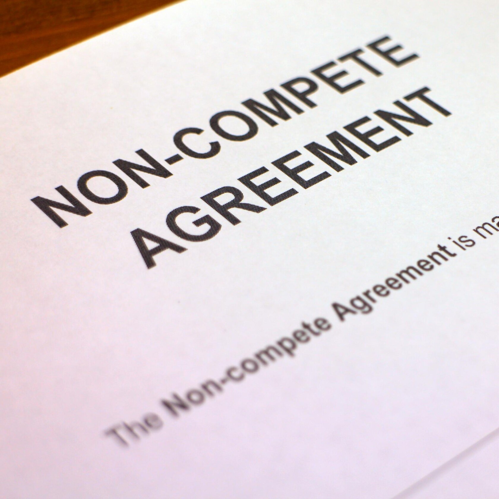 A close-up photo of a document titled "Non-Compete Agreement," often reviewed by lawyers in Chicago, with partial text visible below the heading.
