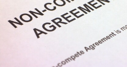 A close-up photo of a document titled "Non-Compete Agreement," often reviewed by lawyers in Chicago, with partial text visible below the heading.