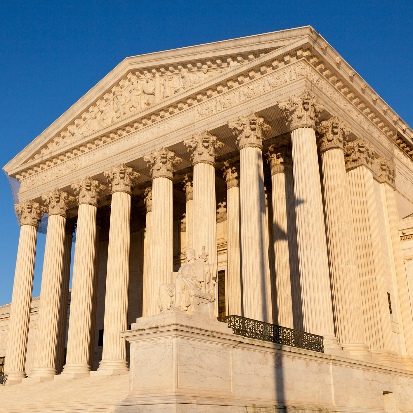 The facade of the United States Supreme Court building features tall columns, a sculpted pediment, and a statue at the entrance, illuminated by sunlight—an inspiring sight for lawyers in Chicago seeking justice.