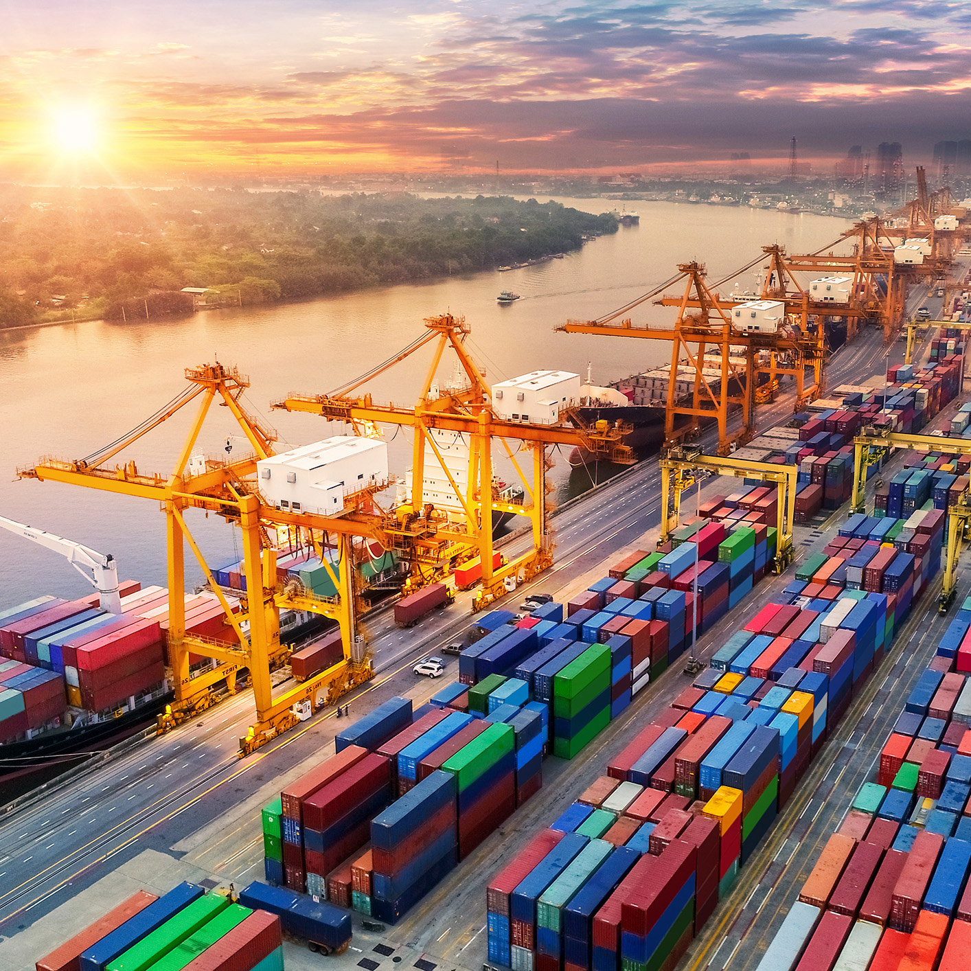 A busy port with large cranes loading shipping containers onto cargo ships at sunset, colorful containers lined up and a river in the background—much like the organized efficiency seen in top law offices or among leading lawyers in Chicago.