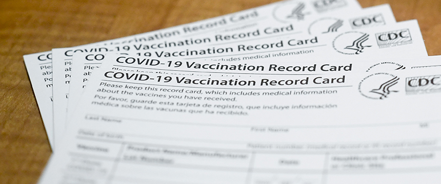 Several CDC-issued COVID-19 Vaccination Record Cards are stacked on a wooden surface, often referenced by Chicago lawyers for litigation support in health-related cases.
