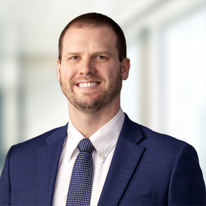 Man in a blue suit and polka dot tie smiling, standing in a brightly lit, professional indoor setting—perfectly representing the confidence and expertise of leading Chicago lawyers.
