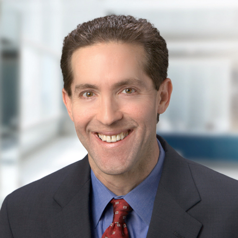 A man in a suit and red tie smiles at the camera in a brightly lit, modern law office, offering litigation support alongside experienced lawyers in Chicago.