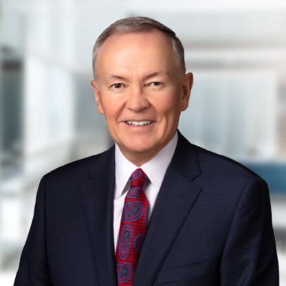 A man in a dark suit, white shirt, and red patterned tie is smiling in an office setting with a blurred background, representing litigation support provided by experienced lawyers in Chicago.