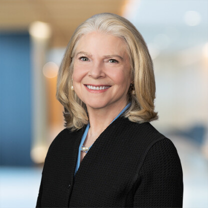 A woman with shoulder-length blonde hair, wearing a black blazer and pearl earrings, smiles at the camera in a professional indoor setting, representing leading chicago lawyers in intellectual property law.