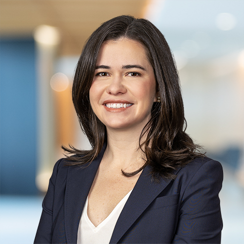 A woman with shoulder-length dark hair wearing a navy blazer and white top, smiling in a modern office setting—representing the professionalism of Chicago lawyers.